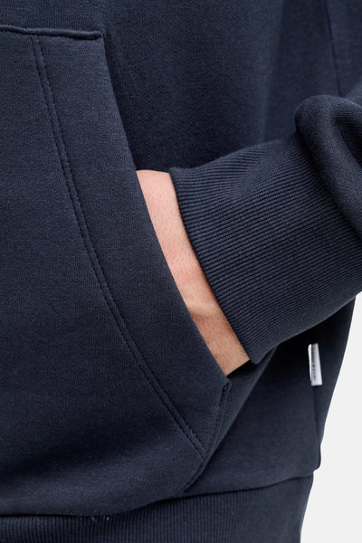 Blauwe hoodie van JACK & JONES, met een hand in de kangoeroezak.