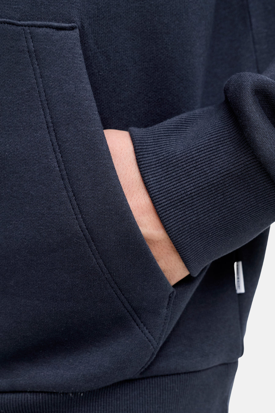 Blauwe hoodie van JACK & JONES, met een hand in de kangoeroezak.