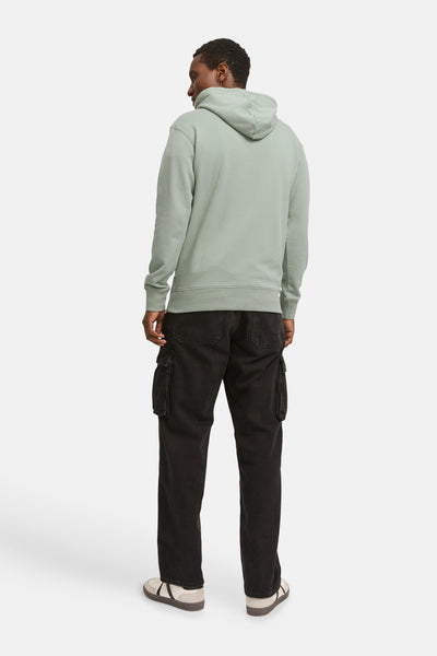 Mintgroene hoodie van Originals by Jack & Jones, met zwarte cargobroek en sportschoenen.