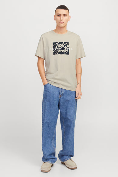 Beige T-shirt met korte mouwen van Originals by Jack & Jones, gedragen met een wijde blauwe jeans en lichtbruine nette schoenen.