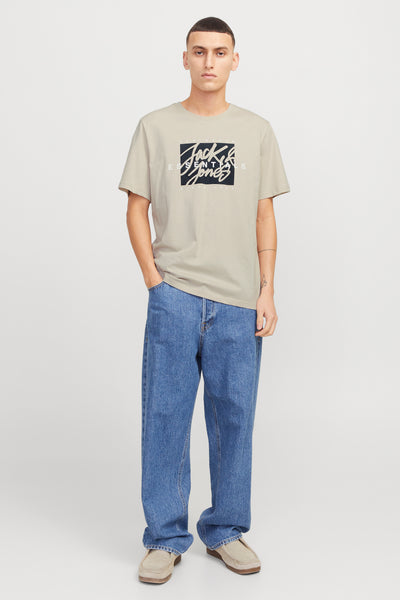Beige T-shirt met korte mouwen van Originals by Jack & Jones, gedragen met een wijde blauwe jeans en lichtbruine nette schoenen.