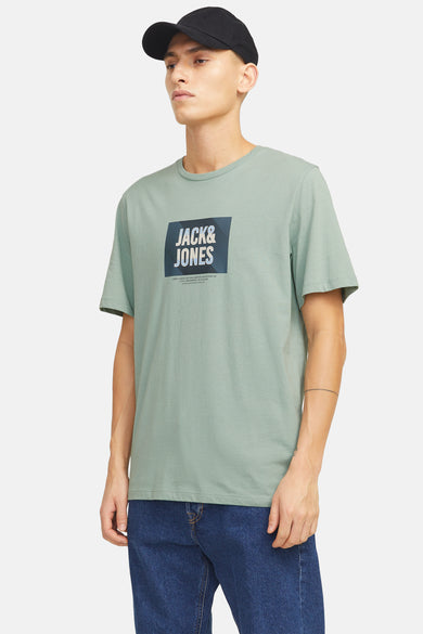 T-shirt vert met JACK & JONES, gedragen met een blauwe broek en zwarte sneakers.