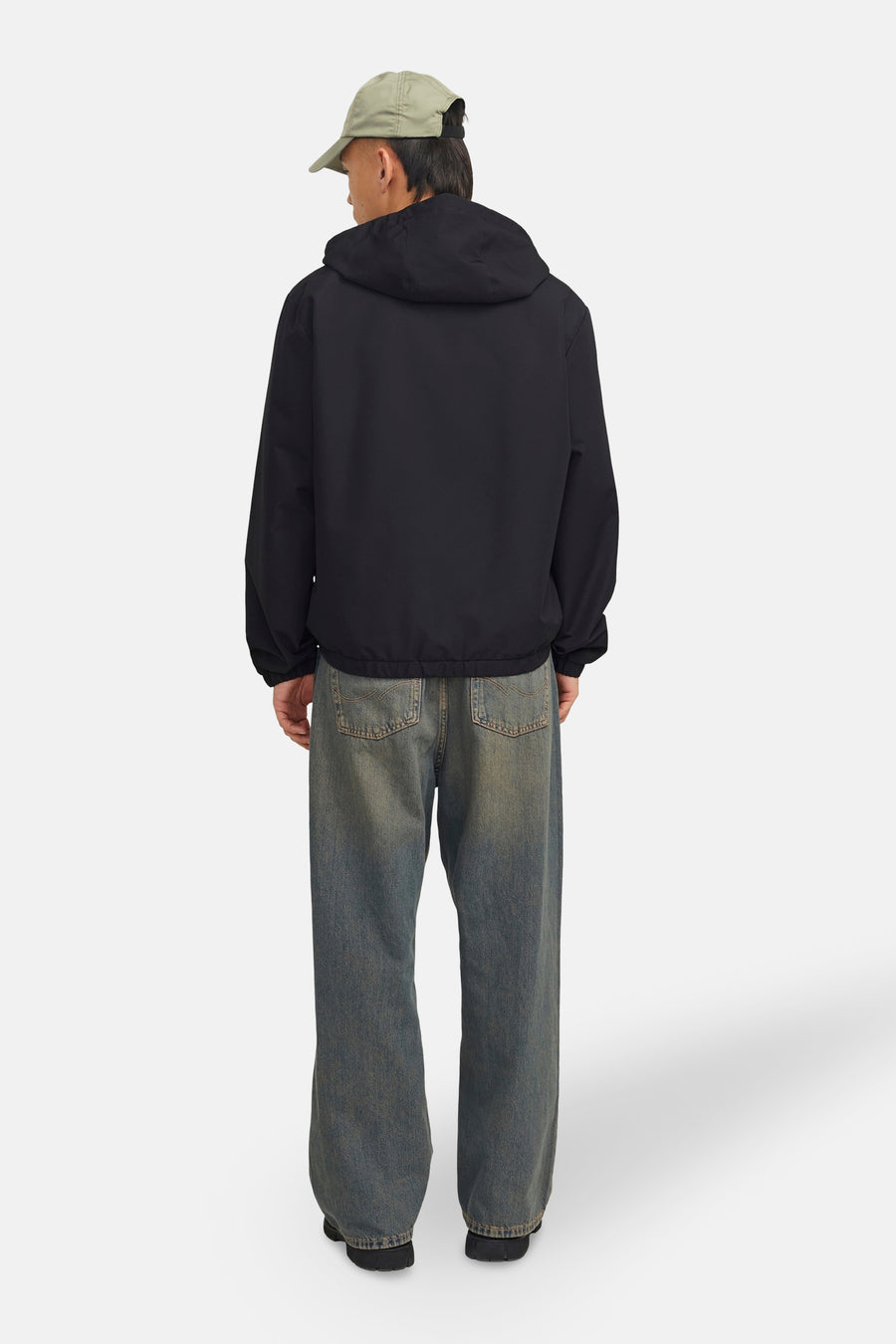 Zwarte regenjas van ORIGINALS BY JACK & JONES, met capuchon, gedragen met een wijde spijkerbroek.