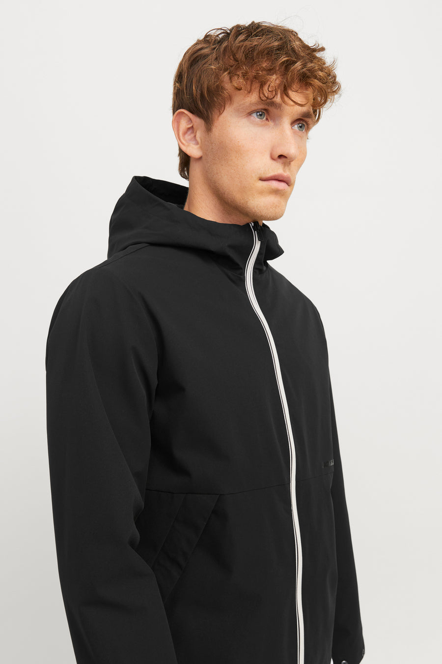 Veste courte noire de JACK & JONES avec capuche et fermeture éclair blanche contrastante.