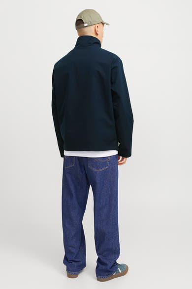 Korte blauwe jas van JACK & JONES, gedragen met een wit T-shirt, een wijde jeans en sneakers.