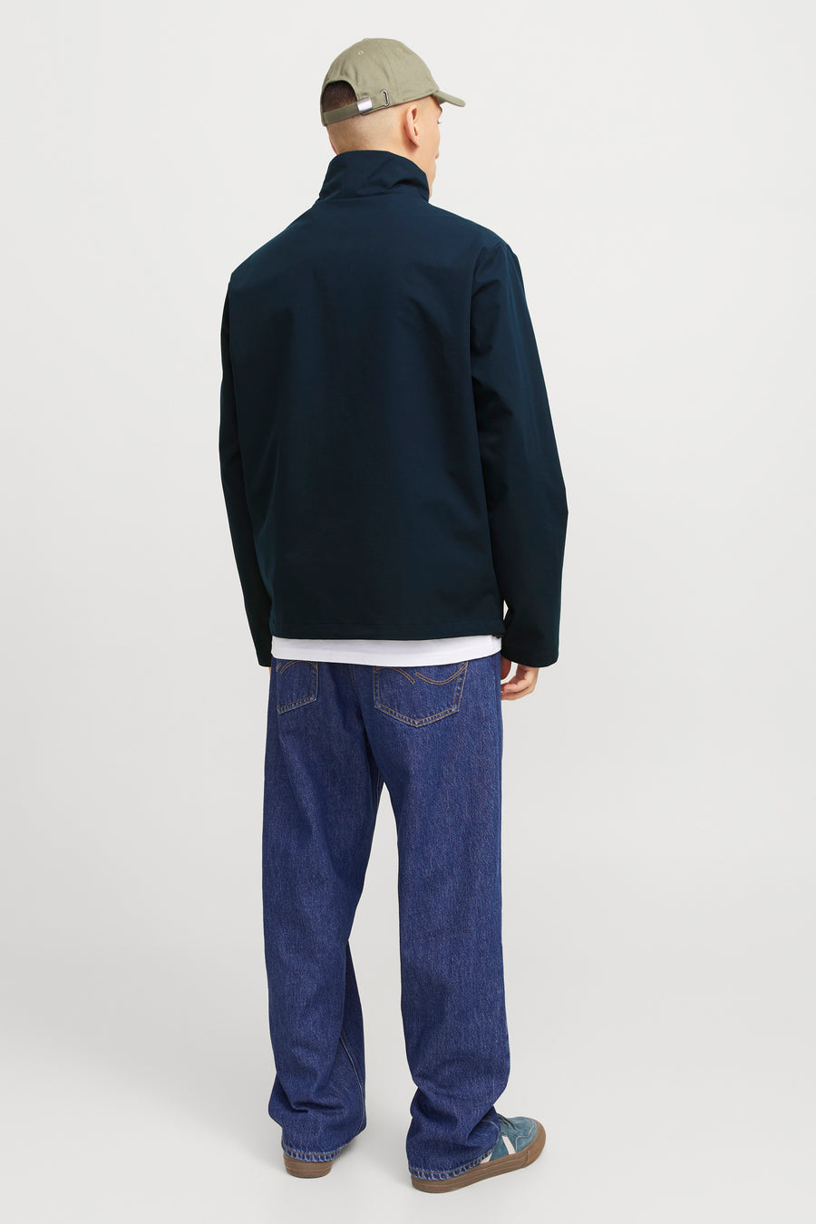 Korte blauwe jas van JACK & JONES, gedragen met een wit T-shirt, een wijde jeans en sneakers.
