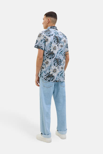Blauw overhemd met korte mouwen en bloemenprint van JACK & JONES, met een blauwe spijkerbroek en witte schoenen.