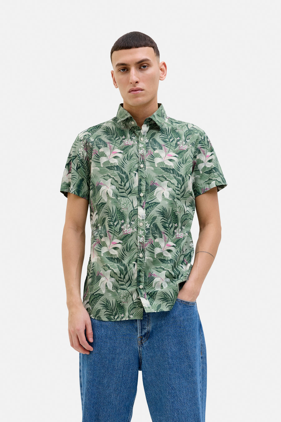 Groen overhemd met korte mouwen en bloemenprint van JACK & JONES, gedragen met een blauwe jeans en witte sneakers.