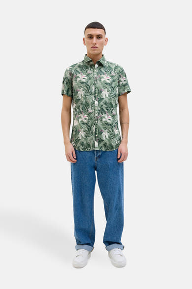 Chemise à manches courtes verte à motif floral de JACK & JONES, portée avec un jean bleu et des baskets blanches.
