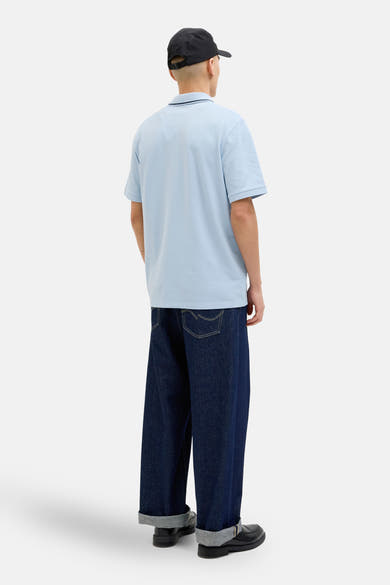 Blauw poloshirt met korte mouwen van JACK & JONES, gedragen met een zwarte broek en een zwarte pet.