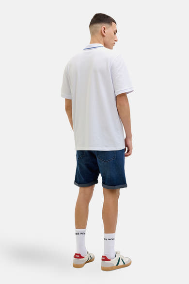 Wit poloshirt met korte mouwen van JACK & JONES, met een kraag met blauwe strepen, gedragen met een spijkerbroekshort en sneakers.