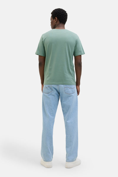 Kaki T-shirt met korte mouwen van JACK & JONES, gedragen met een lichtblauwe jeans en witte schoenen.