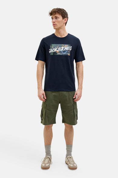 T-shirt à manches courtes bleu foncé de JACK & JONES, avec un motif floral rectangulaire sur le devant, porté avec un short cargo vert.