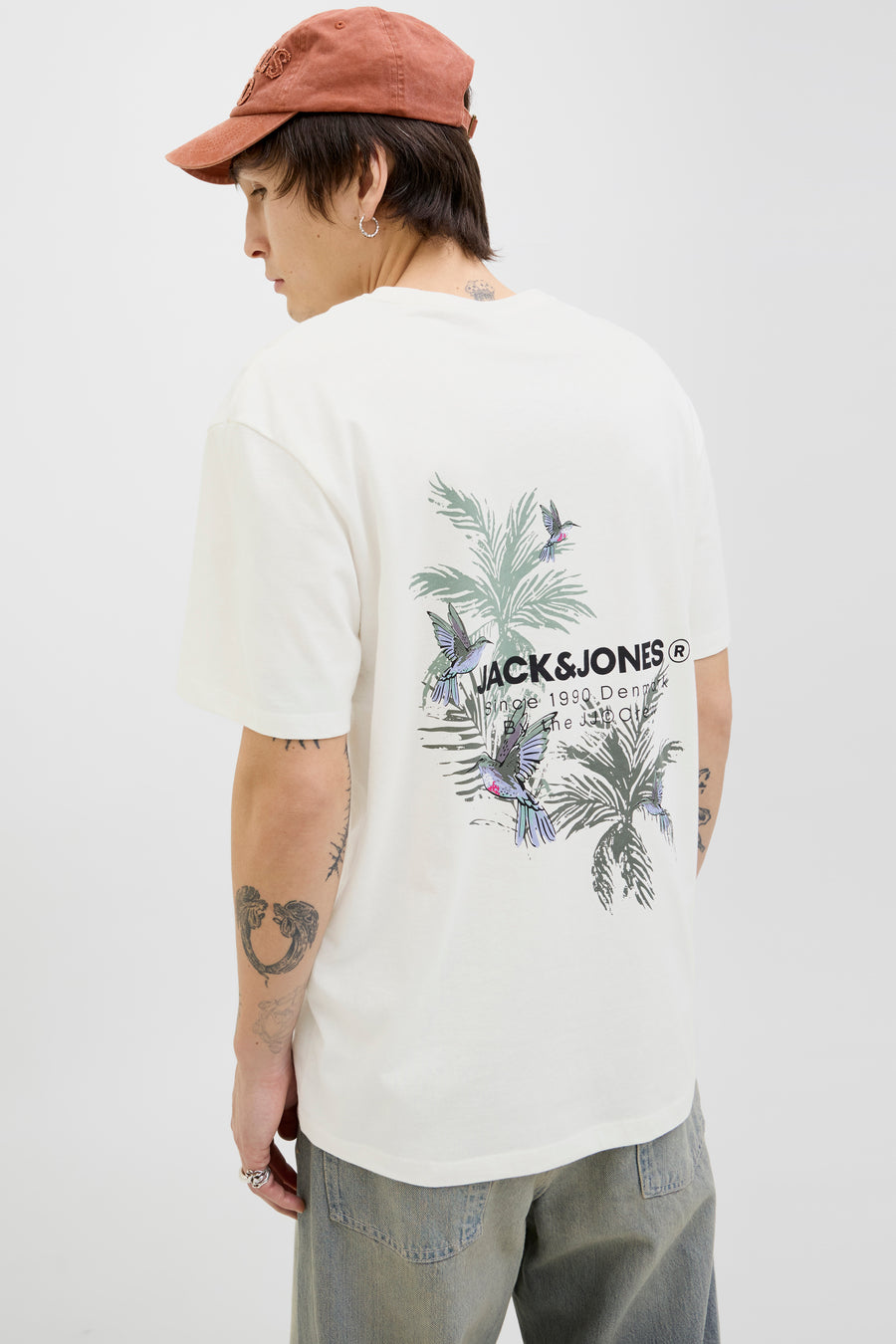 Wit T-shirt met korte mouwen van ORIGINALS BY JACK & JONES, bloemen- en vogelprint op de rug, gedragen met een casual broek en een pet.