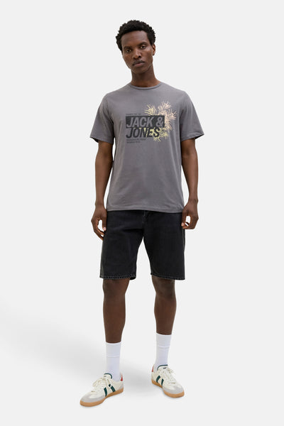 T-shirt à manches courtes gris de JACK & JONES, avec un imprimé sur le devant, porté avec un short noir et des baskets blanches.
