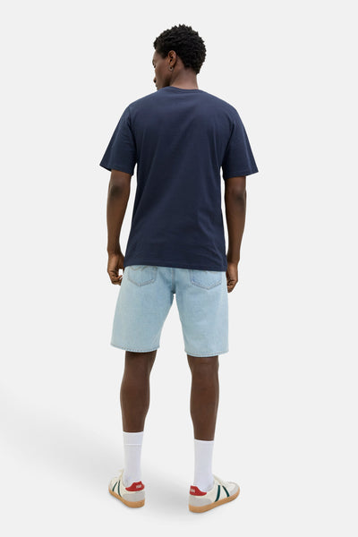T-shirt à manches courtes bleu de JACK & JONES, porté avec un short en jean clair et des baskets basses.
