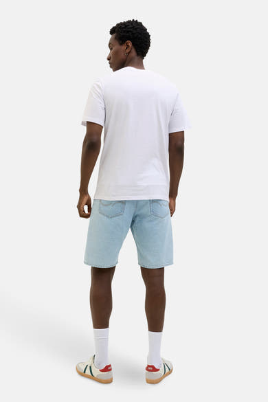 T-shirt à manches courtes blanc de JACK & JONES, porté avec un short en jean bleu clair et des baskets rétro.