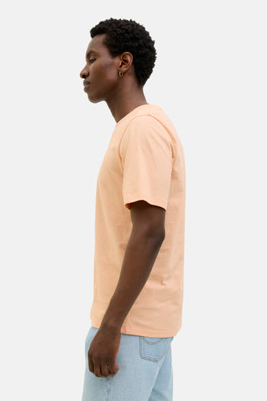 Oranje T-shirt met korte mouwen van ORIGINALS BY JACK & JONES, gedragen met een lichte spijkerbroek, zijaanzicht.