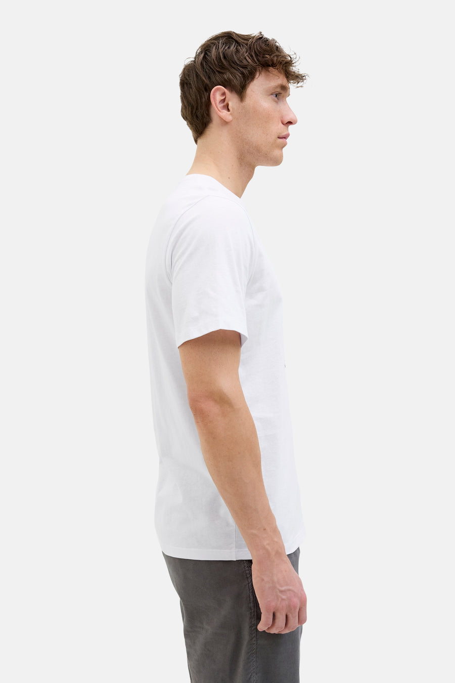 T-shirt blanc à manches courtes par ORIGINALS BY JACK & JONES, porté avec un pantalon gris, vue de profil.
