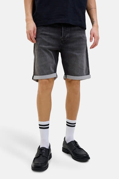 Short en jeans noir délavé par JACK & JONES JEANS INTELLIGENCE, porté avec chaussettes blanches rayées et chaussures noires.