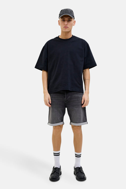 Short en denim noir de Jack & Jones Jeans Intelligence, porté avec un t-shirt noir, des chaussettes rayées et des chaussures noires.