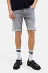 Grijze spijkerbroek van JACK & JONES, gedragen met een zwart oversized T-shirt, gestreepte sokken en zwarte bootschoenen.