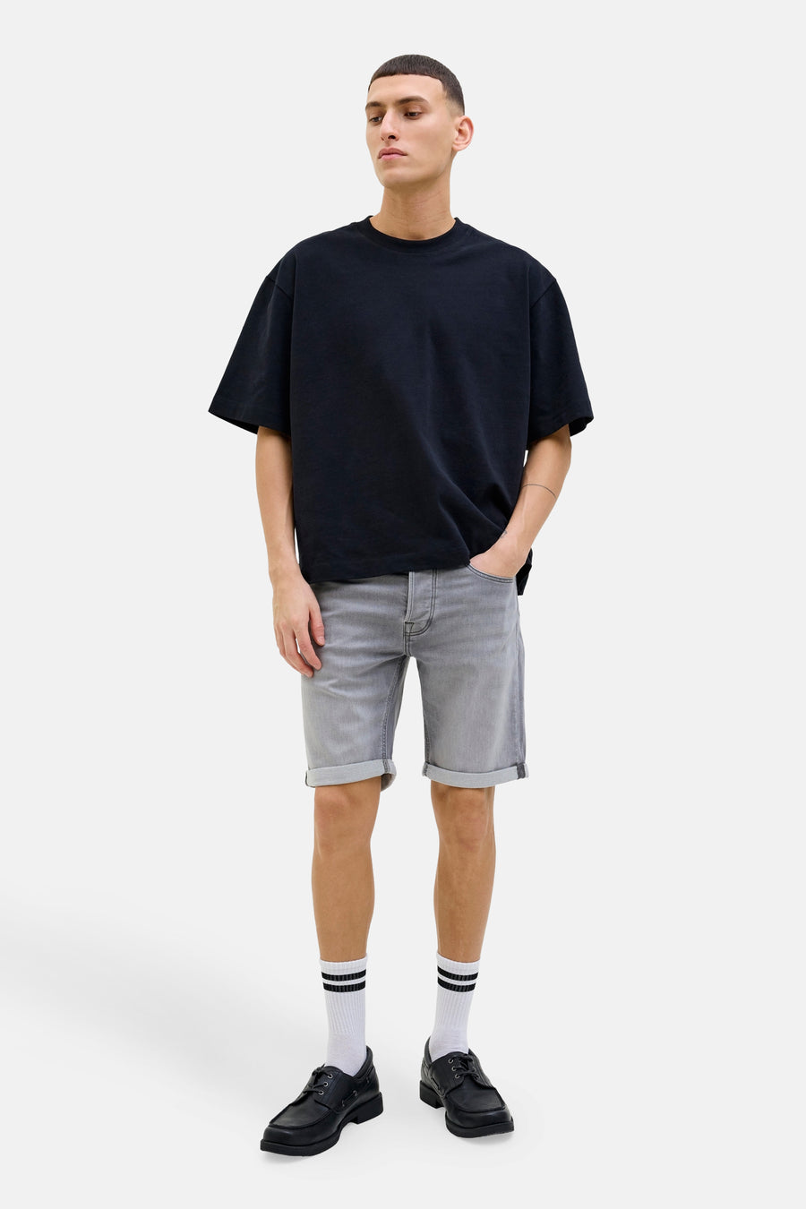 Short en jean gris de JACK & JONES, porté avec un t-shirt noir oversize, des chaussettes rayées et des chaussures bateau noires.