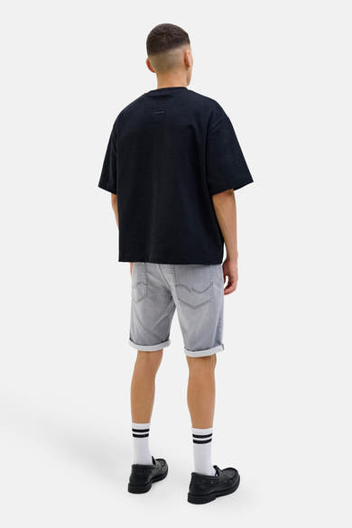 Korte grijze spijkerbroek van JACK & JONES, gedragen met een zwart T-shirt en zwarte loafers.