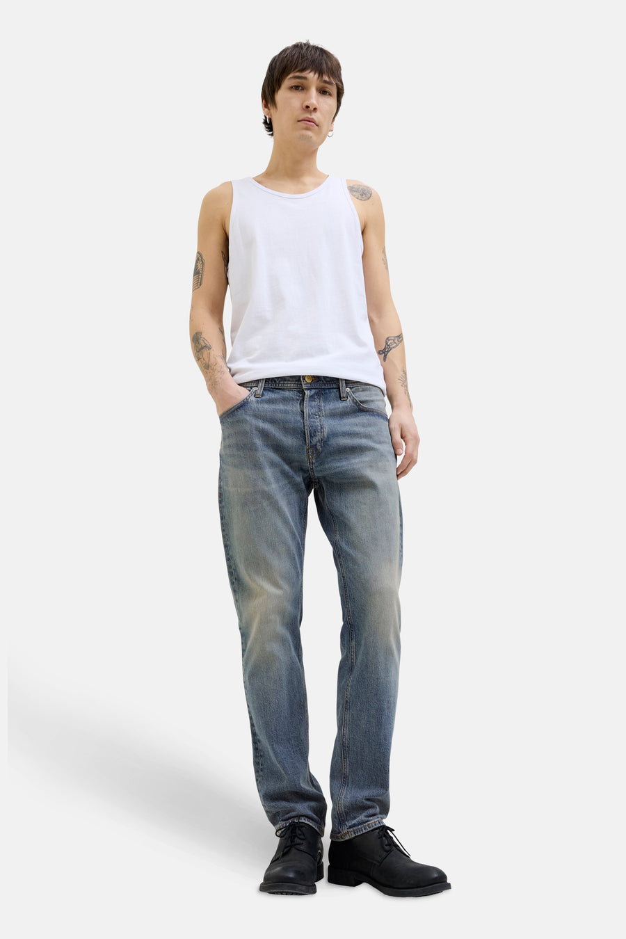 Taps toelopende spijkerbroek in middinblauw denim van Jack & Jones, gedragen met een witte tanktop en zwarte schoenen.