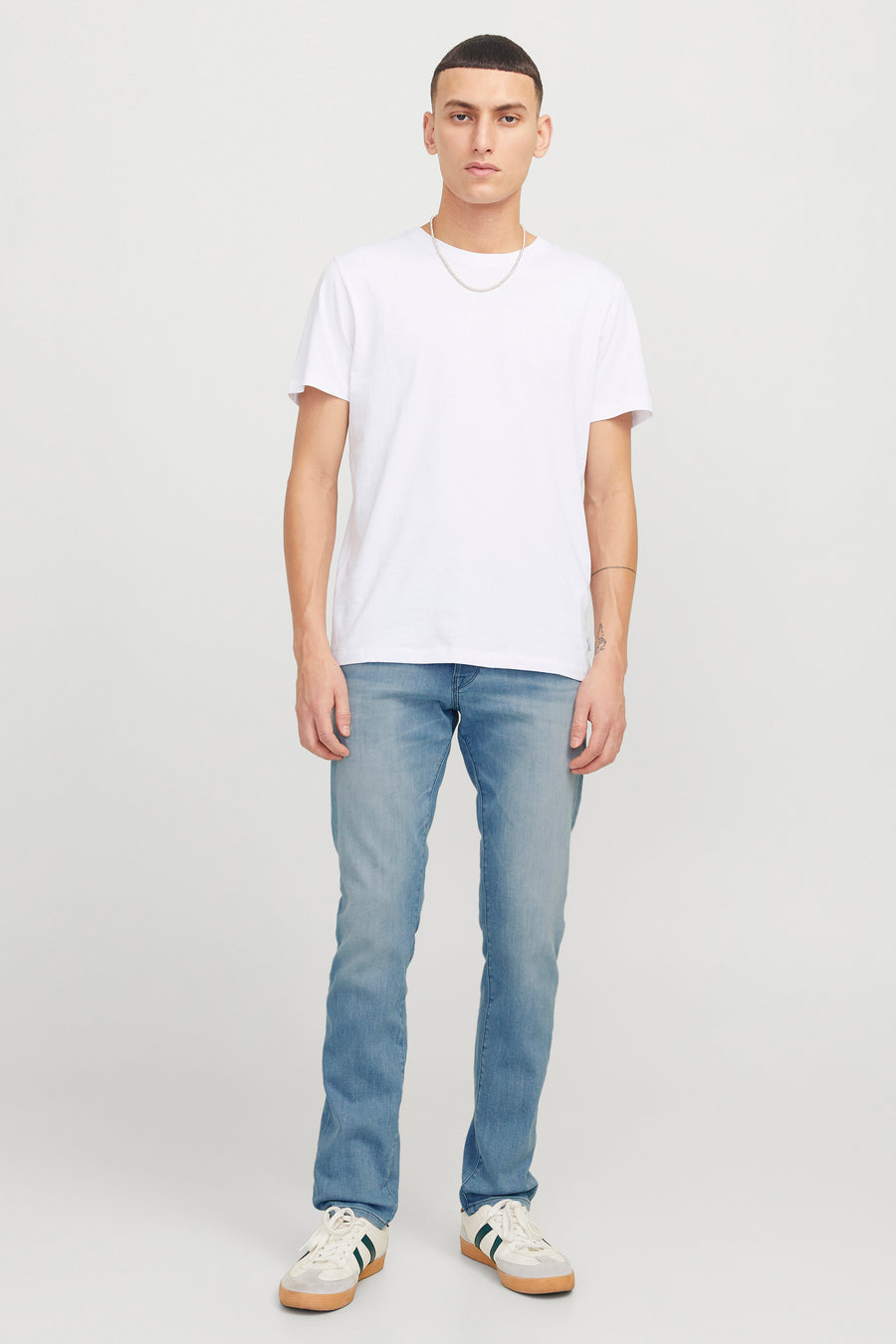 Lichtblauwe slim fit jeans van JACK & JONES JEANS INTELLIGENCE, gedragen met een wit T-shirt en sportschoenen.