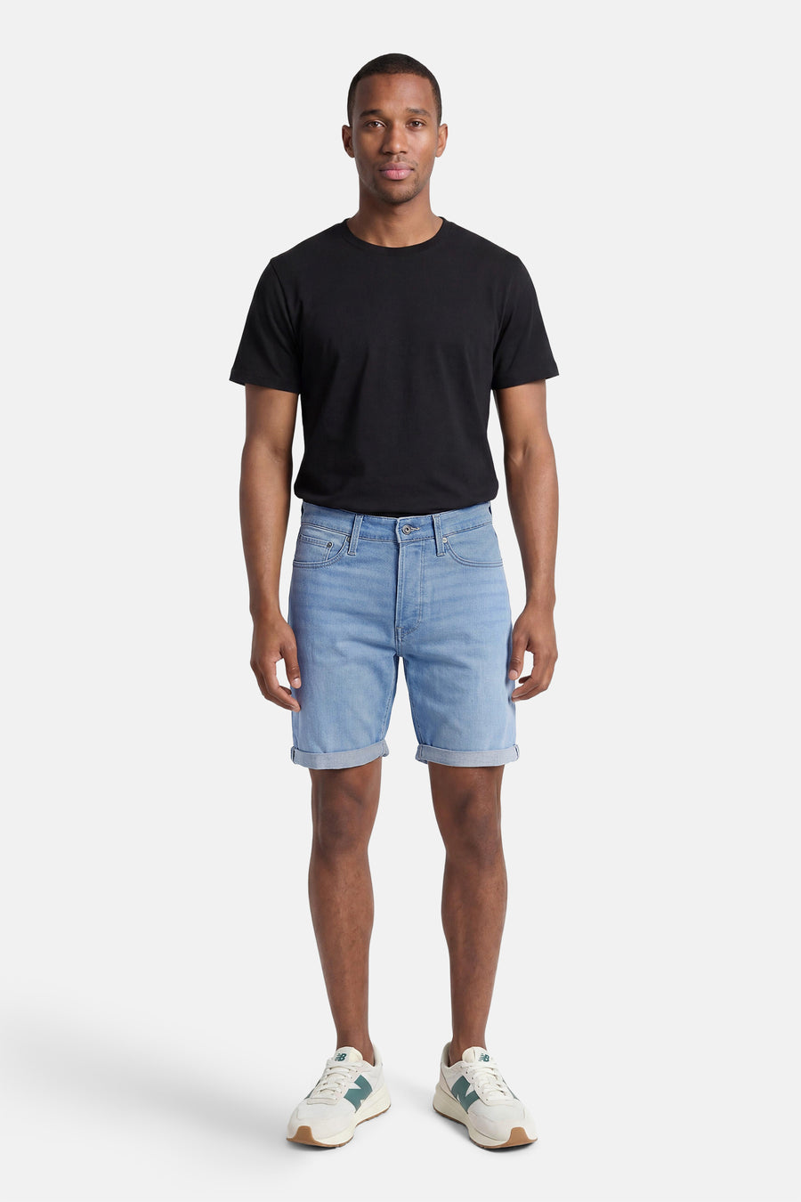 Short en jean bleu clair de JACK & JONES, porté par un homme avec un t-shirt noir et des baskets blanches, ourlet retroussé.