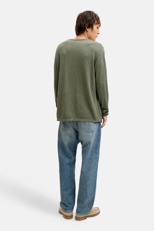 Groene trui met ronde hals van PREMIUM by JACK & JONES, gedragen met een lichtblauwe jeans en beige schoenen.