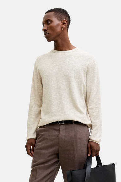 Pull à col rond beige de PREMIUM by JACK & JONES, porté avec un pantalon marron et un sac noir.
