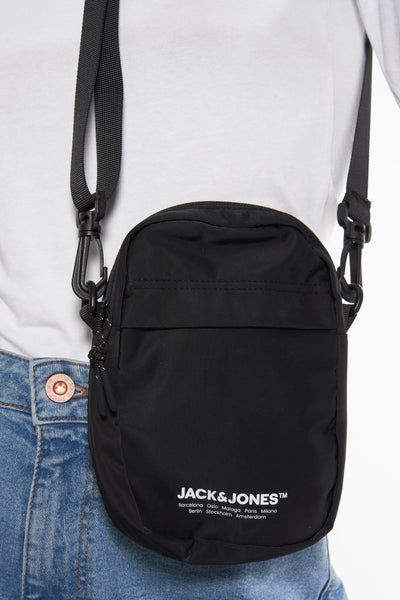 Sac à bandoulière noir de ACCESSORIES BY JACK & JONES, porté avec un t-shirt blanc et un jean.
