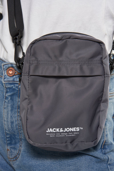 Grijze schoudertas van ACCESSORIES BY JACK & JONES, gedragen over een blauwe jeans.