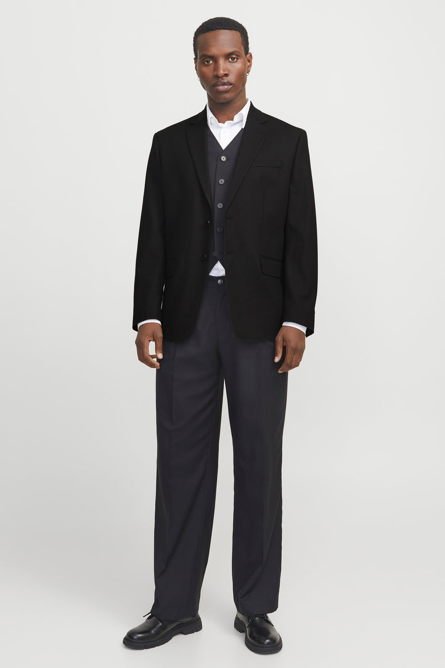 Blazer noir par PREMIUM by JACK & JONES, porté avec un gilet et pantalon coordonnés, sur fond clair.
