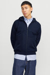 Donkerblauwe regenjas van JACK & JONES, gedragen over een gestreept overhemd en een blauwe spijkerbroek.