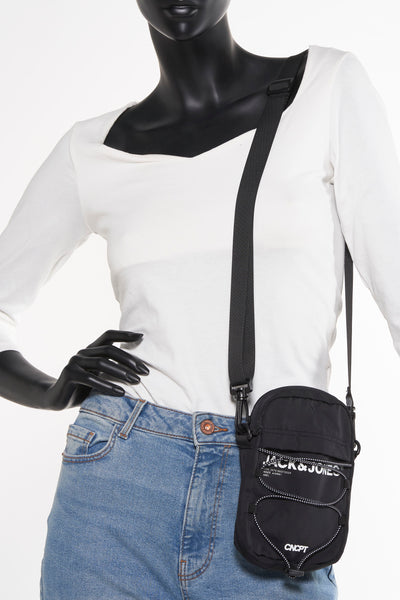 Zwarte schoudertas van ACCESSORIES BY JACK & JONES gedragen door een model met spijkerbroek en witte top.