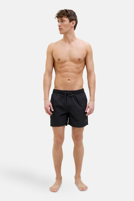 Short de bain noir de JACK & JONES JEANS INTELLIGENCE, porté par un homme torse nu.
