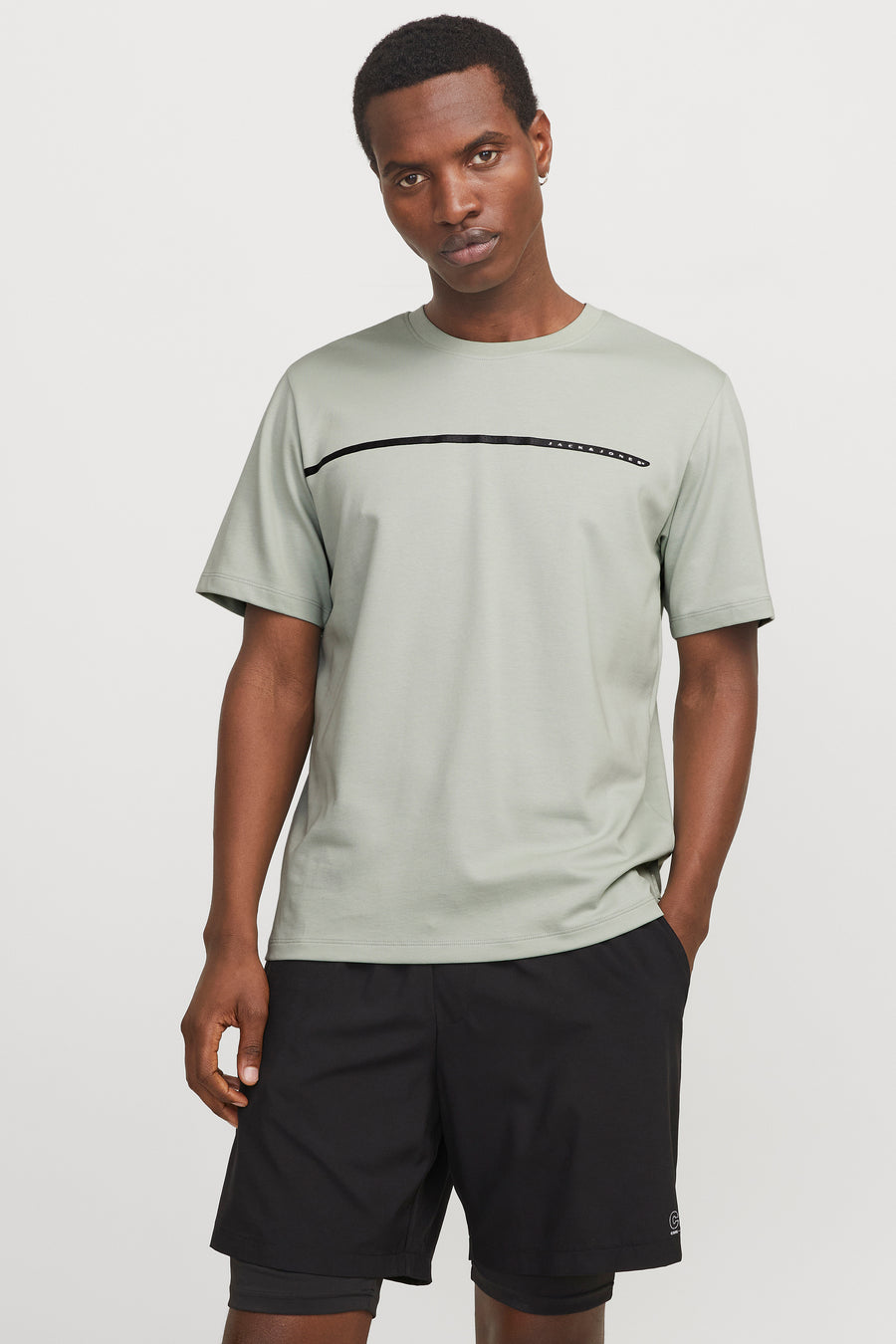 Groen T-shirt met korte mouwen van JACK & JONES, met horizontale streep op de voorkant, gedragen met een zwarte korte broek.