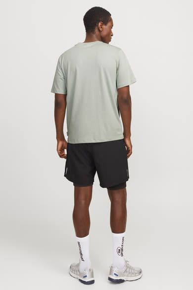 Groen T-shirt met korte mouwen van JACK & JONES, gedragen met een zwarte sportbroek en zilveren hardloopschoenen.