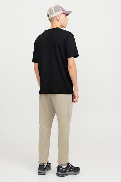 Zwart T-shirt met korte mouwen van JACK & JONES, gedragen met een beige broek en zwarte sneakers.