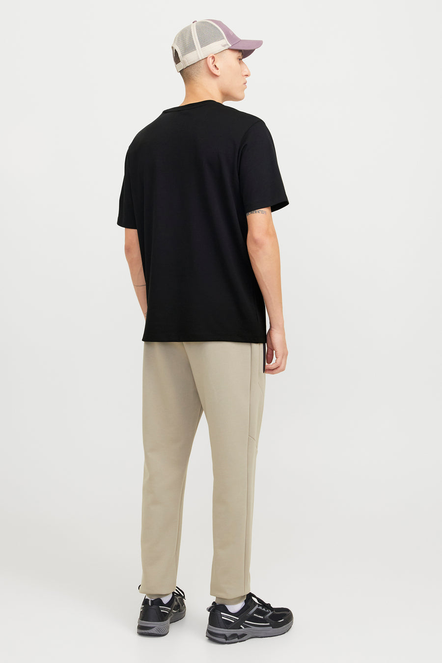 Zwart T-shirt met korte mouwen van JACK & JONES, gedragen met een beige broek en zwarte sneakers.