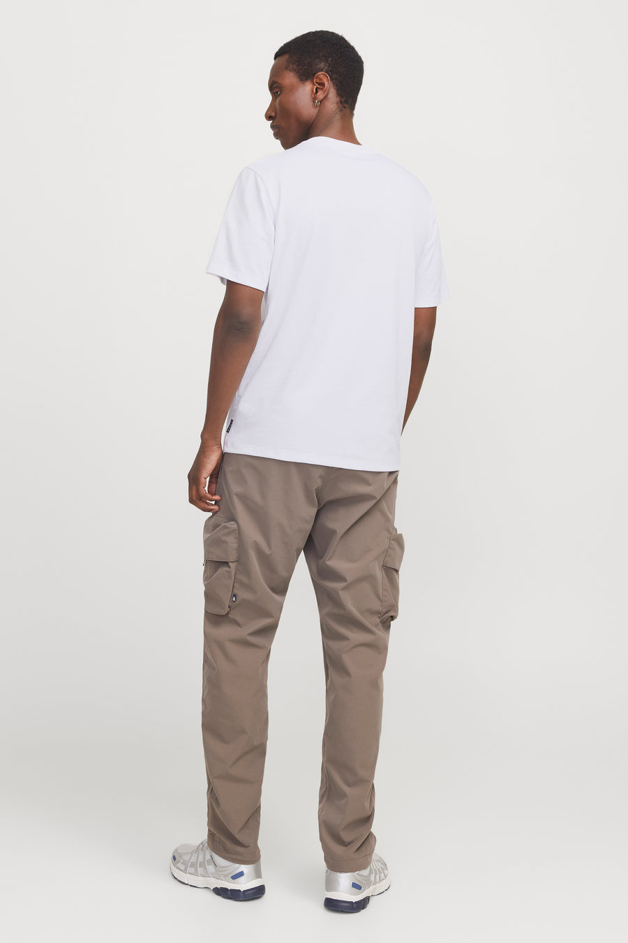 Wit T-shirt met korte mouwen van JACK & JONES, gedragen met een bruine cargobroek en zilveren sneakers.