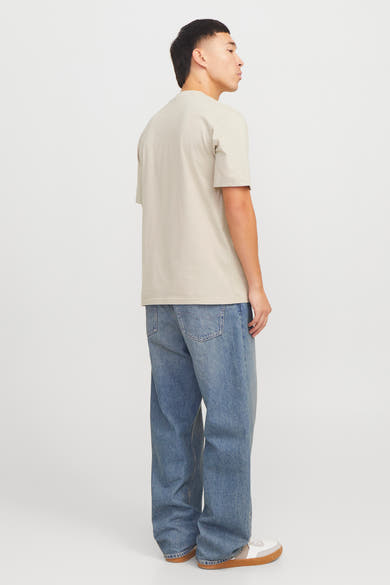 Beige T-shirt met korte mouwen van Originals by Jack & Jones, gedragen met een wijde blauwe jeans en sneakers.