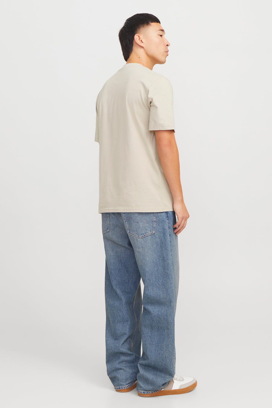 Beige T-shirt met korte mouwen van Originals by Jack & Jones, gedragen met een wijde blauwe jeans en sneakers.