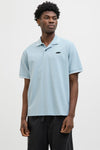 Blauw poloshirt met korte mouwen van JACK & JONES, gedragen met een wijde zwarte broek en zilveren sneakers.