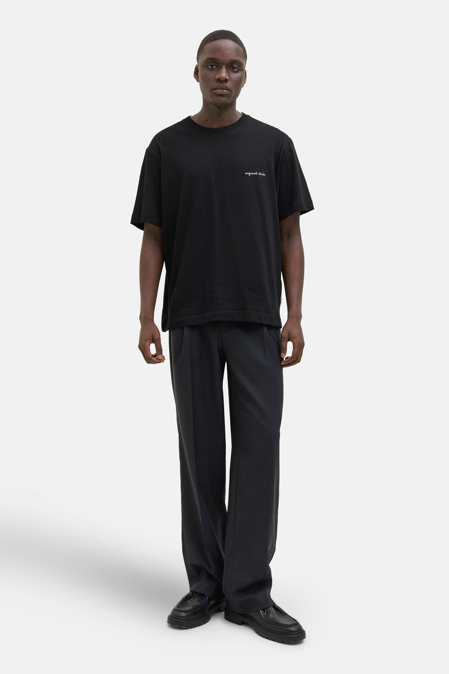 Zwart T-shirt met korte mouwen van ORIGINALS BY JACK & JONES gedragen met een zwarte wijde broek en zwarte schoenen.