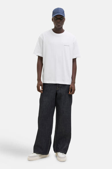 T-shirt blanc à manches courtes par ORIGINALS BY JACK & JONES, porté avec un pantalon ample.