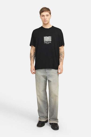 Zwart T-shirt met korte mouwen van ORIGINALS BY JACK & JONES met witte grafische print, gedragen met een verbleekte spijkerbroek.